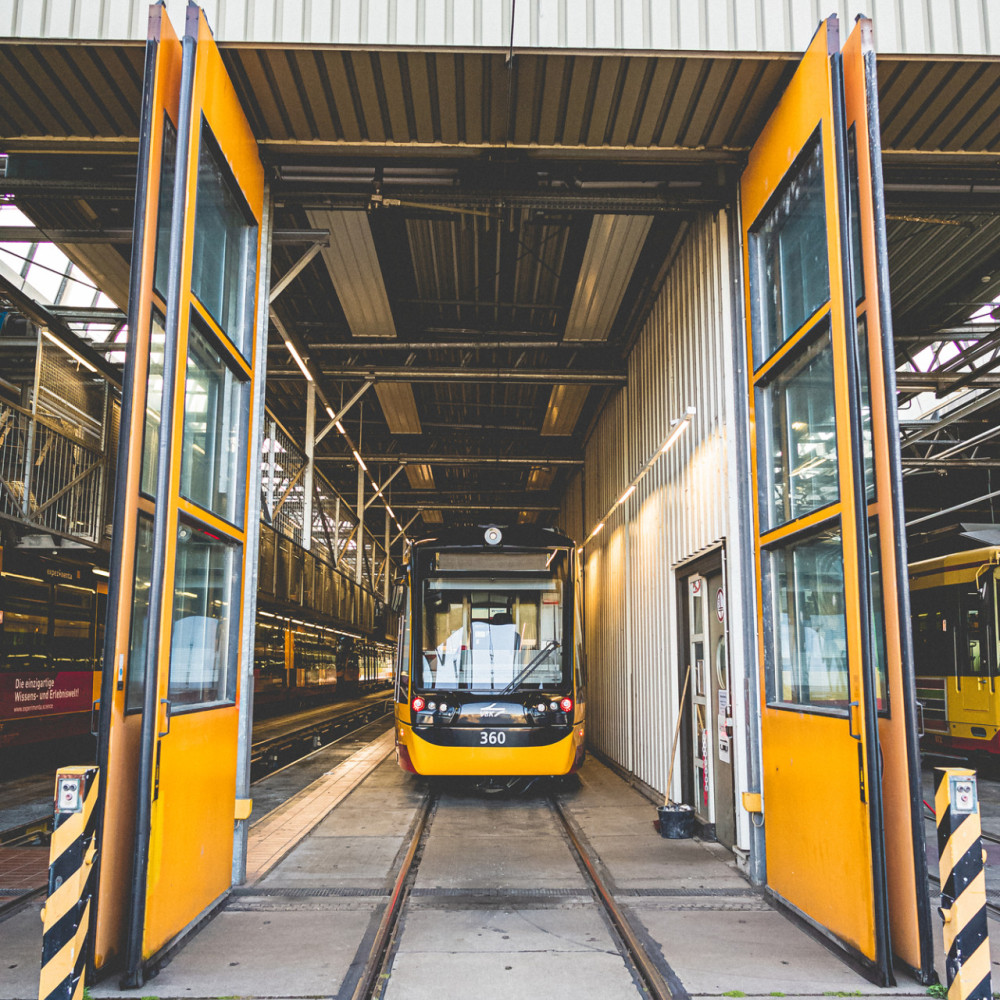 Eine Bahn steht in der Halle des Bahndepots und die Türen des Depots sind offen.