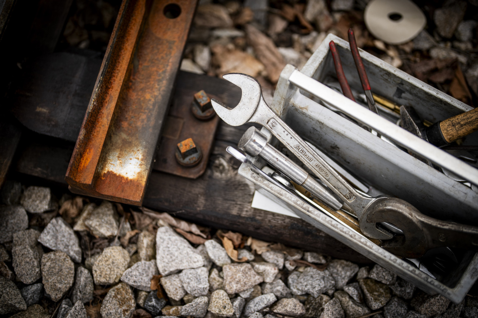 Werkzeuge in einer Kiste neben Gleisen.