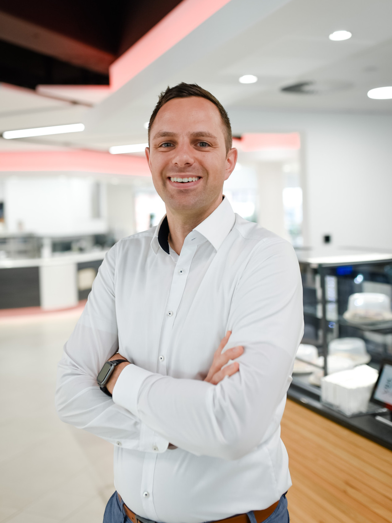 Der Küchenchefleiter steht lächelnd im weißen Hemd da.