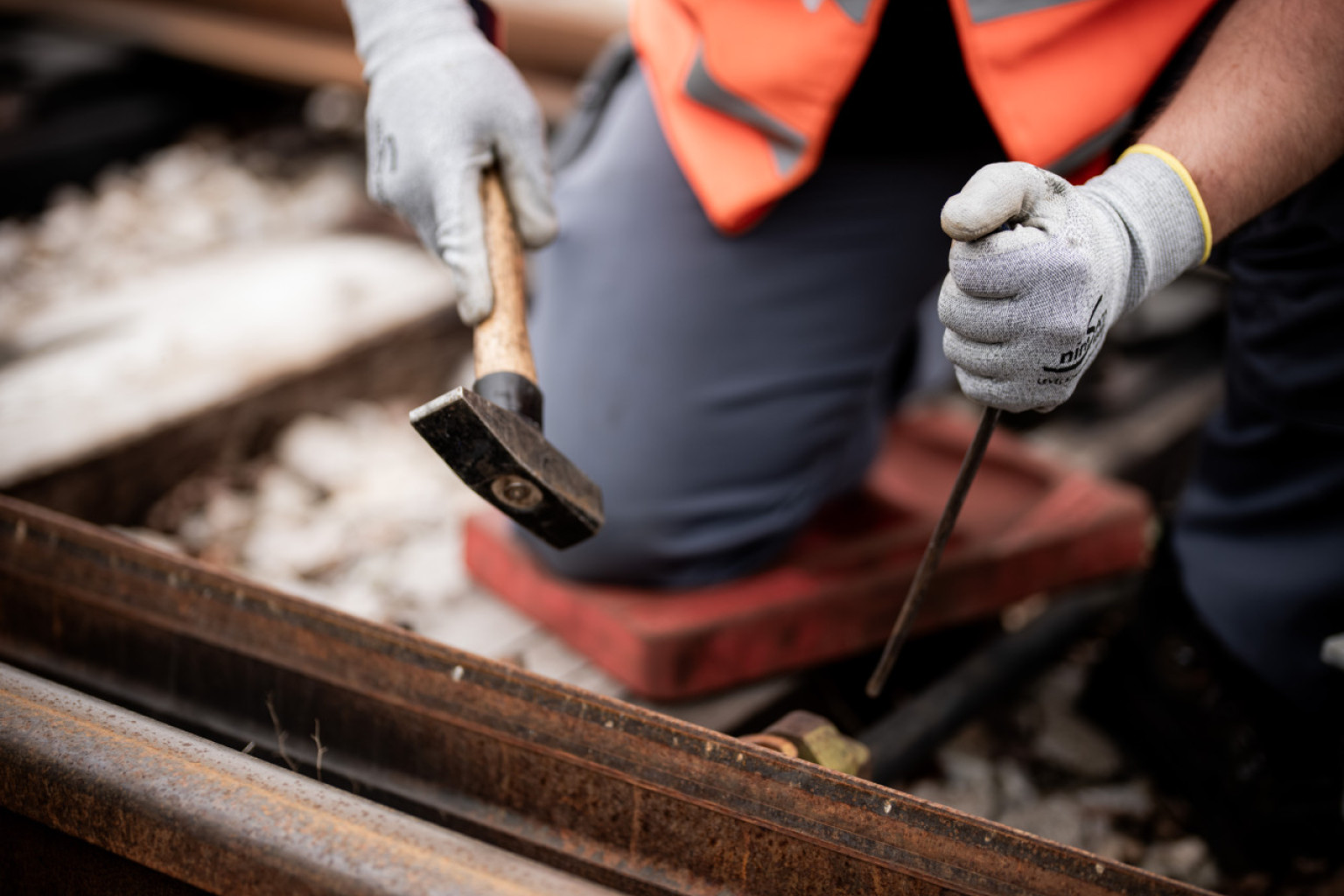Ein Mitarbeiter arbeitet an einer Gleise mit Hammer und Nagel.