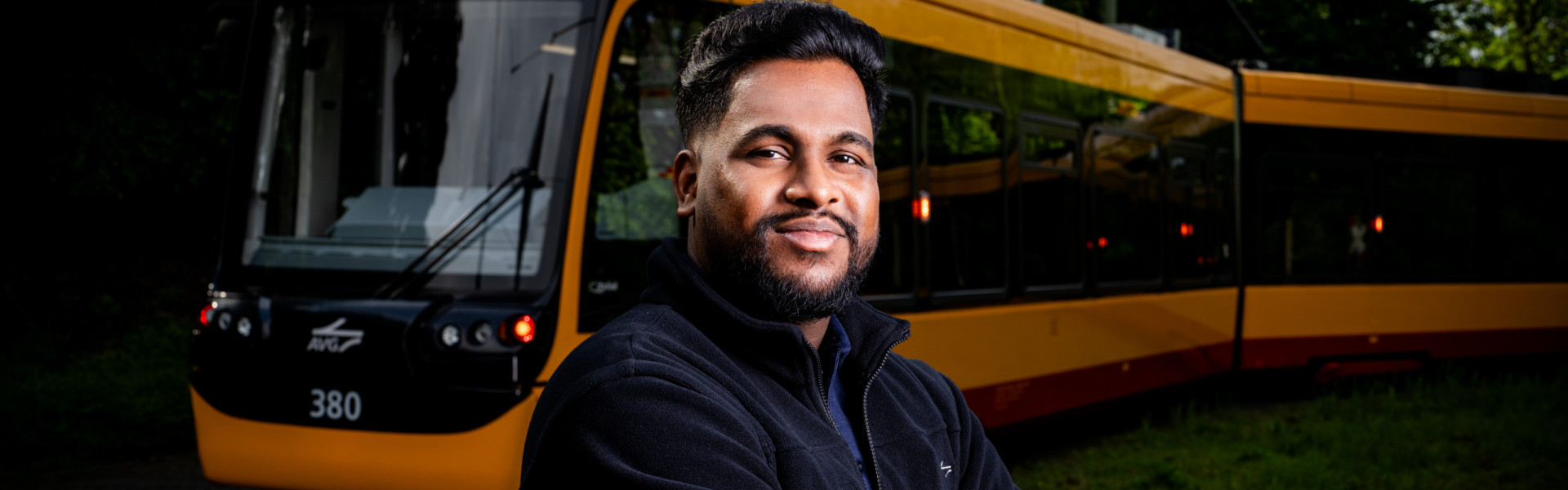 Ein Straßenbahnfahrer steht im freien vor einer Bahn.