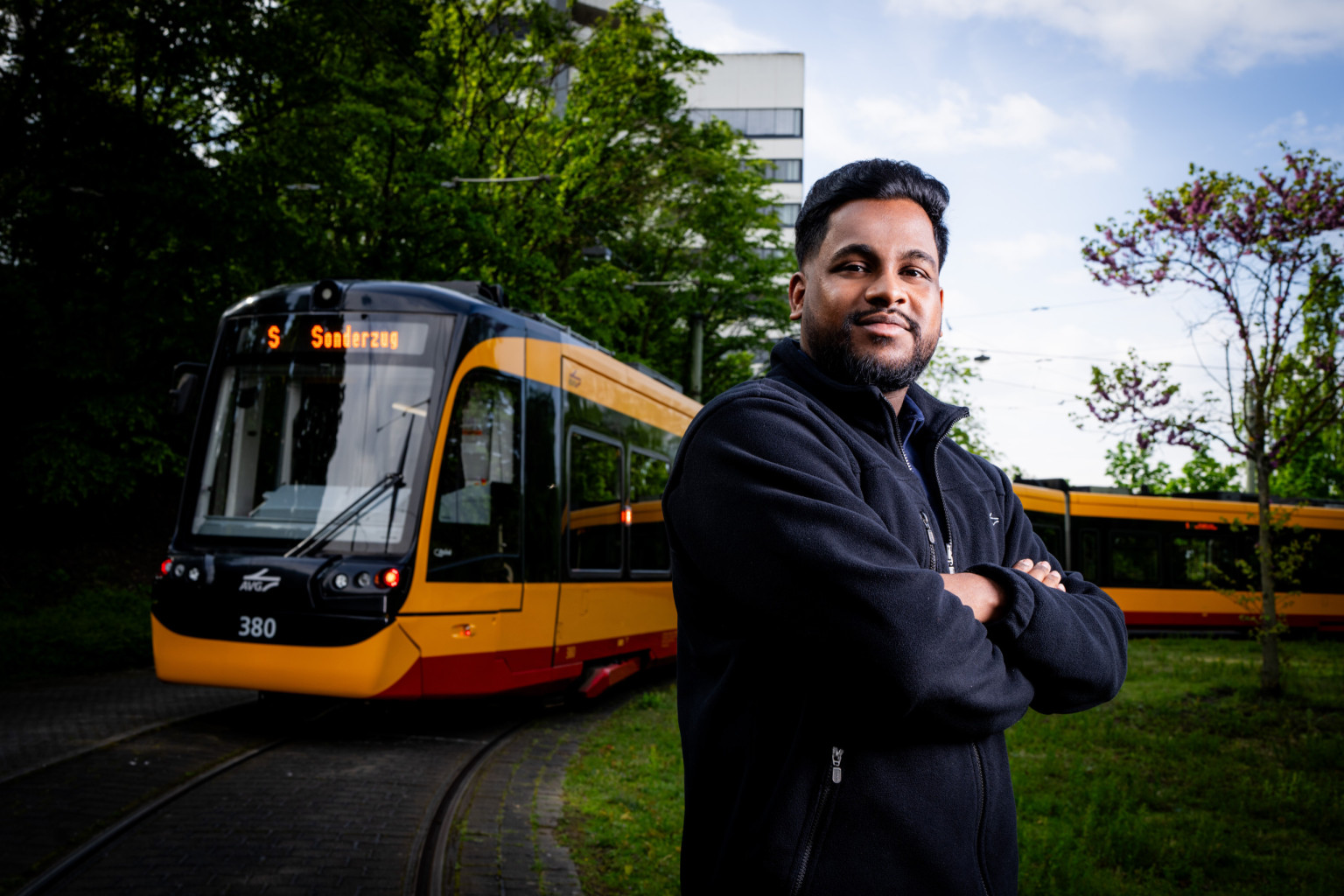 Ein Straßenbahnfahrer steht im freien vor einer Bahn.