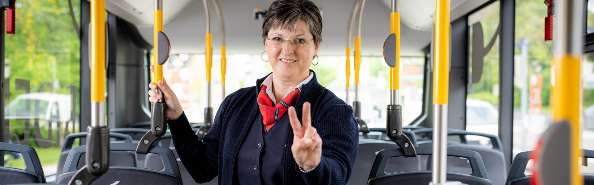 Eine Bahnfahrerin in einem Bus mit der #TeamV-Peace Pose.