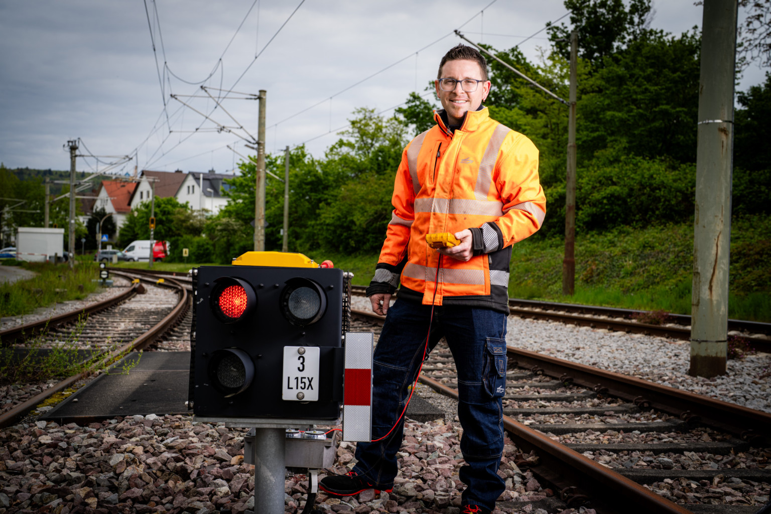 Ein Mitarbeiter auf den Gleisen steht neben einem Lichtsignal.